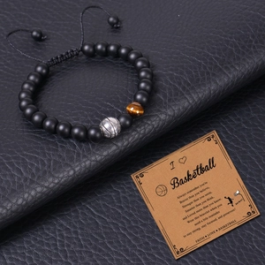 Macro shot of 8mm tiger eye bead and silver basketball charm on a woven adjustable bracelet