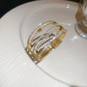 Détail d'un bracelet ouvert doré multicouche avec motifs de cœurs et pavé de diamants