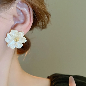 Detailed close-up of a sweet white resin flower earring with a gold center on a model