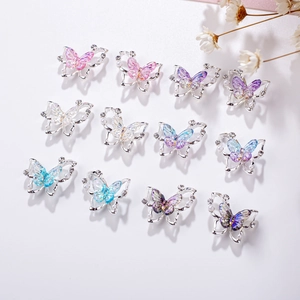 Detailed flat lay of twelve butterfly nail charms with aurora crystals and small pearls