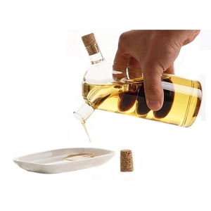 Dual-layer glass oil and vinegar dispenser with cork stoppers being poured
