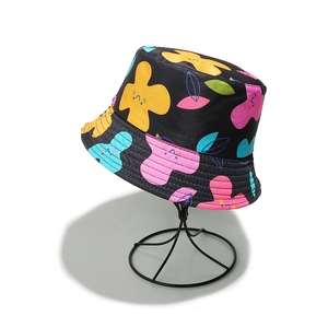 Close-up of a black bucket hat featuring colorful smiling flower prints on a display stand