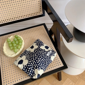 Close-up of cotton floral makeup bag with Nordic pattern on a rustic rattan chair