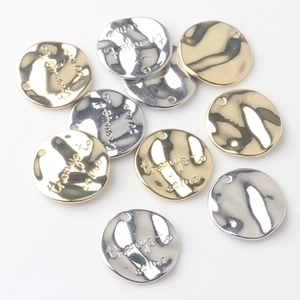 Macro shot of silver and gold round metal pendants with hammered texture and inscriptions