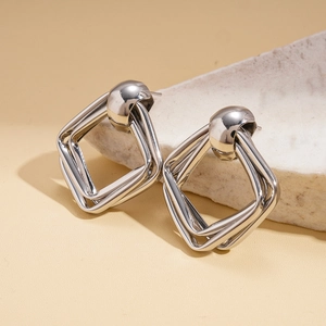 Detailed view of layered geometric diamond silver stud earrings on a stone prop