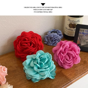 Detailed view of assorted fabric flower hair claws in red, pink, blue, and purple tones