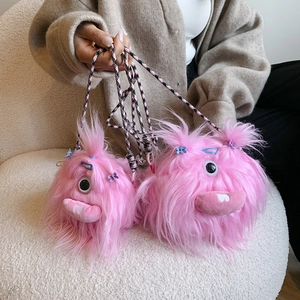 Detailed macro view of pink plush monster bag with braided strap on white fabric