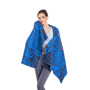 Blue microfiber beach towel with black spiral pattern shown as a shawl on a model