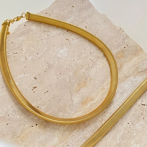 Minimalist gold woven mesh chain necklace and bracelet set on a natural stone surface