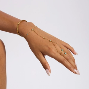 Detail von goldenem Fingerarmband mit blauen Edelsteinen und Ring-Set an der Hand