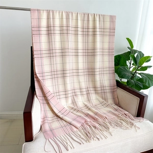 Detail of pink and beige plaid scarf texture with soft tassels on a white armchair