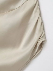 Gros plan détaillé du haut en satin beige montrant le plissage et les coutures