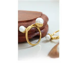 Detailed macro view of gold twist ring with two 0.8cm white pearls on wooden base