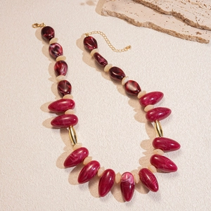 Detail of burgundy acrylic beads with marble texture and golden spacers on a necklace