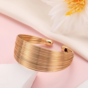 Detail of multi-layer golden wire cuff bracelet with spherical ends on stone base
