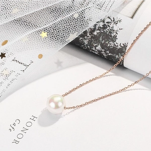 Rose gold titanium necklace with large iridescent pearl pendant on an open book