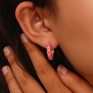 Macro shot of pink checkered enamel hoop earrings with gold finish on a model