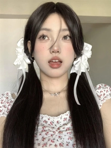 Close-up of white satin bow hair clips with long ribbons on a double ponytail style