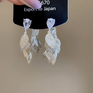 Close-up of silver earrings with teardrop zircon and layered hollow leaf tassels