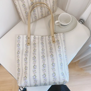 Close-up of floral tote bag with matching pouch on a white table in soft lighting