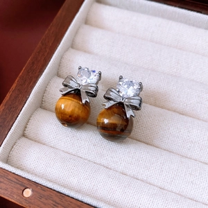 Detail view of tiger eye heart earrings with zircon bow on soft velvet lining