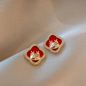 Close-up of red clover earrings with golden deer motifs and sparkling crystal accents