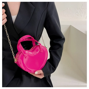Close-up of heart-shaped crossbody bag in rose pink patent leather with gold chain