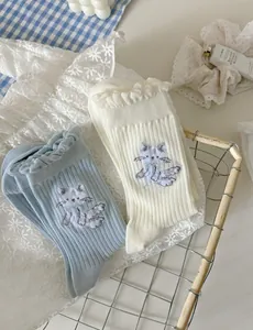 Détail de la broderie chat et des bords volantés sur chaussettes en coton