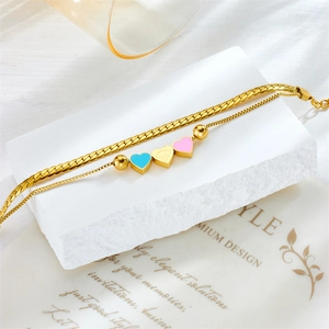 Gold double-layered chain bracelet with blue and pink enamel heart pendants on stone decor