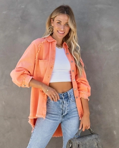 Detail of distressed raw hem on a vibrant coral oversized knit shirt for casual women's style