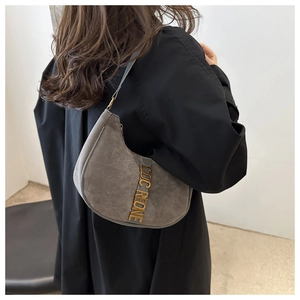 Detailed side view of grey suede hobo bag with wide shoulder strap and gold logo