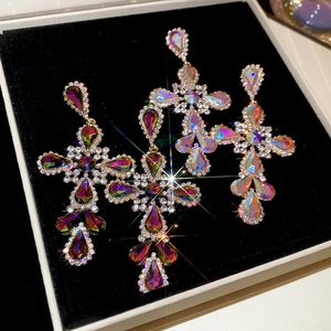 Macro shot of silver needle cross earrings with vibrant colorful rhinestones on velvet