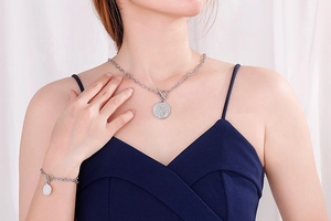 Detail of silver stainless steel necklace and bracelet set with coin pendants and T-bar toggle