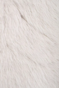 Macro shot of high-density white faux fur texture showing soft plush fibers on the vest