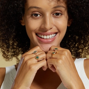 Close-up of model wearing four gold S925 silver rings with green moss agate and zircon stones