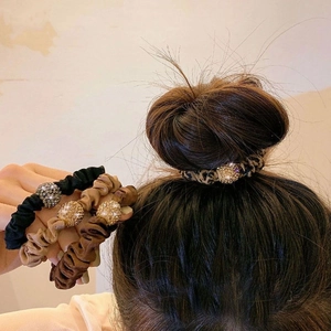 Detail of pleated fabric hair ties with rhinestone ball accents on a bun hairstyle