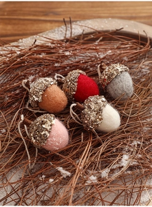 Detailed view of handmade felt acorn ornaments with sequins on festive wooden base