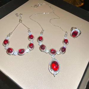 Exquisite silver jewelry set featuring red gemstone flowers with zircon accents on a display pad
