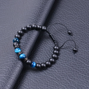 Macro detail of blue tiger eye and matte onyx beads on a black braided cord bracelet