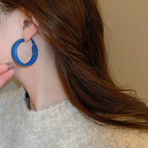 Detail view of bold Klein Blue circular hoop earrings featuring a glossy polished finish