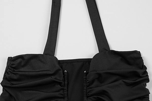 Detail of black ruched dress with U-neck design and metallic bead embellishments