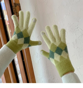 Close-up of green argyle knit gloves with touchscreen-compatible fingertips on hands