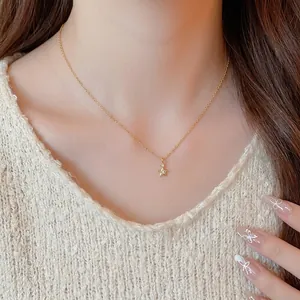 Elegante collana con ciondolo a stella dorata e zircone indossata da una modella su un maglione