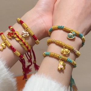 Close-up of woven red and blue lucky horse bracelets with gold charms and enamel details