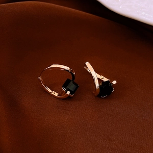 Macro shot of gold-plated irregular cubic earrings with black square-cut gemstones