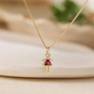 Macro detail of gold necklace featuring a cute girl pendant with pink and clear crystals