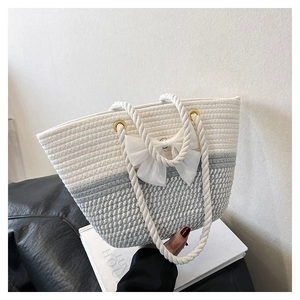 Detail of hand-woven tote bag showing mixed white and grey cotton rope texture with bow