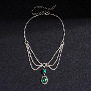 Detailed view of multilayer silver necklace with green emerald-cut crystal pendants
