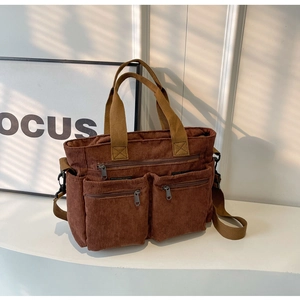 Macro shot of brown corduroy tote bag showing multiple pockets and detachable strap