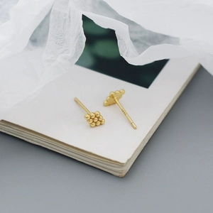 Macro shot of S925 silver golden bead cluster earrings on an open book page
